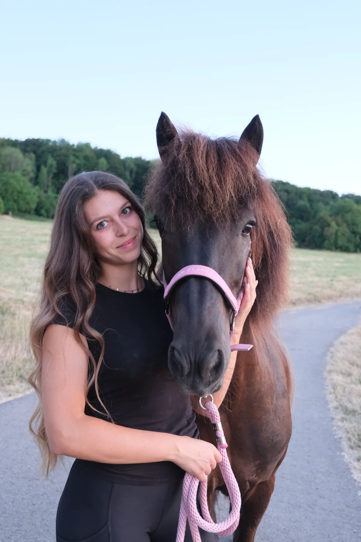 Luana Zawadzki mit ihrer schwarzen Islandstute auf einem Feldweg.